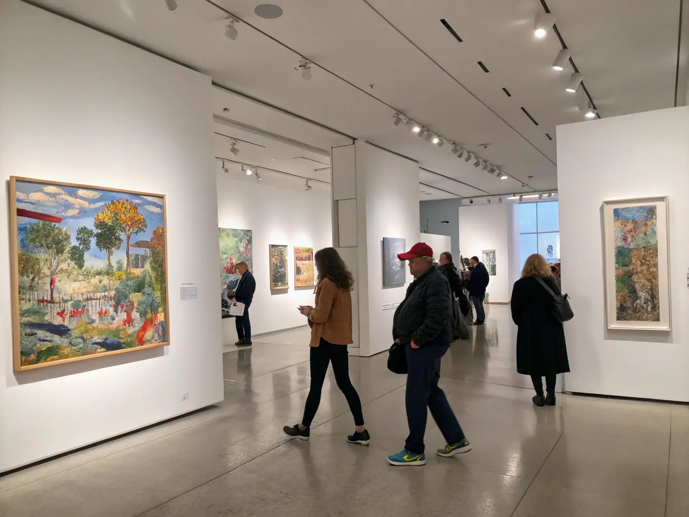 An indoor gallery space filled with colorful paintings and sculptures, with visitors engaging with the artwork, highlighting an Art Exhibition organized by ASS BRIVE LA GAILLARDE EN FETE.